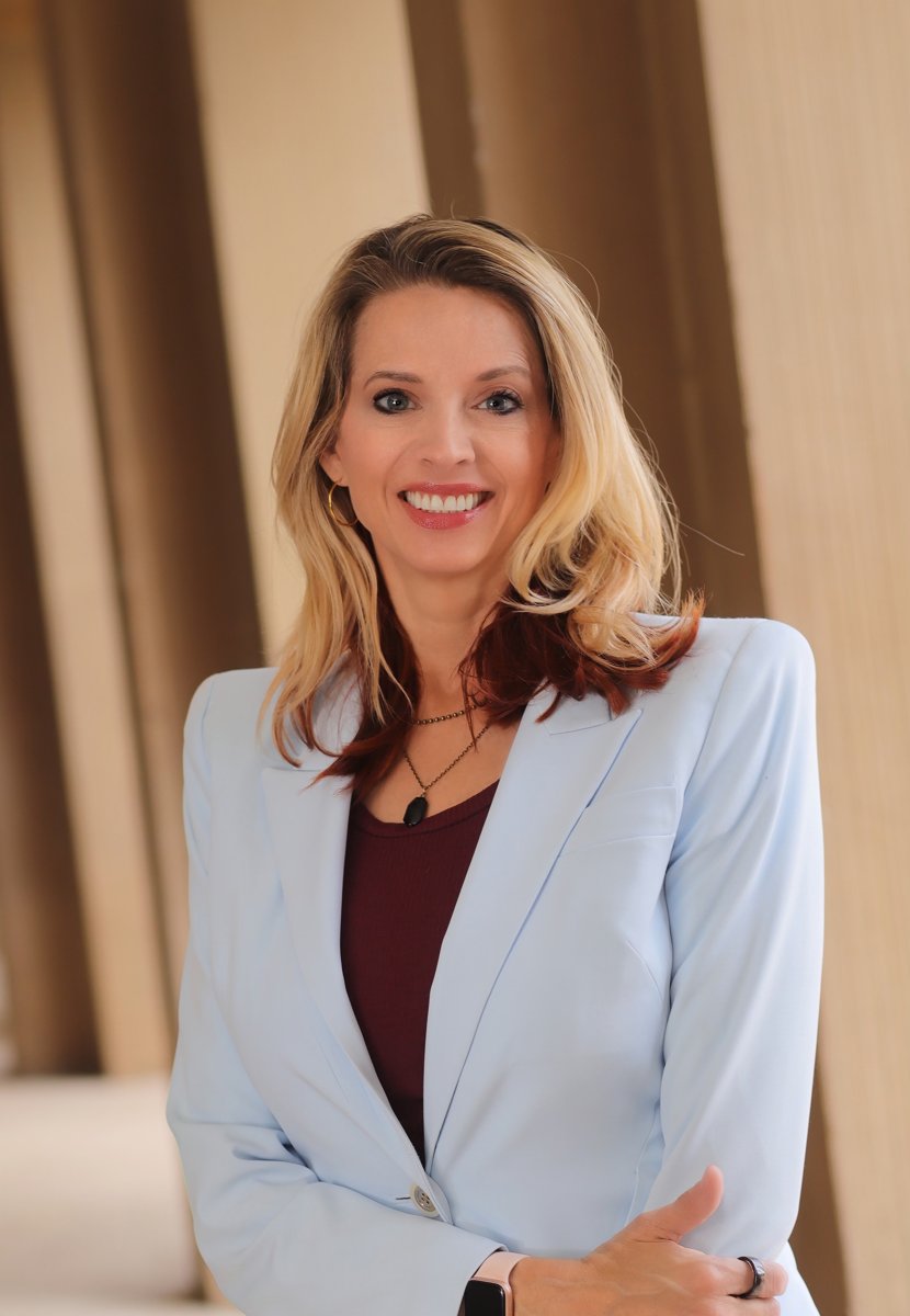 Gina Wilt smiling, wearing a pale blue blazer